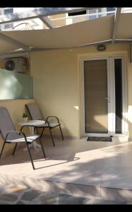 un patio con 2 sillas, una mesa y una puerta de cristal en Fiosal Apartments 2, en Skiathos