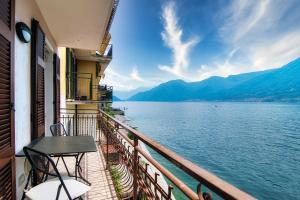 a balcony with a table and chairs next to the water at Da Flora Wonderful Lakefront View in Colonno
