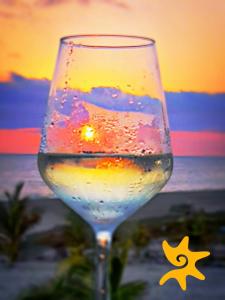 een glas wijn met de zonsondergang op de achtergrond bij Villa Star of the Sea in Barra de Navidad