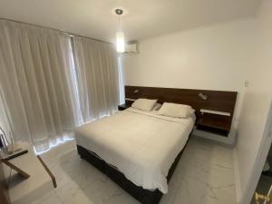 a bedroom with a large bed with white sheets at Departamento Don Miguel Claro in Santiago