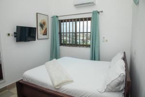 a bedroom with a bed and a window at Résidences Inaya in Cotonou