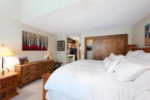a bedroom with a large white bed with a wooden headboard at Tamarron HighPoint 552 in Durango +40 photos