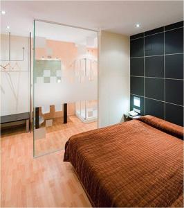 1 dormitorio con 1 cama grande y pared de cristal en Hotel Area Serrano, en Buniel