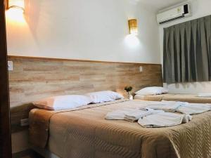 two beds in a hotel room with towels on them at Pousada Bem Viver in Ubatuba