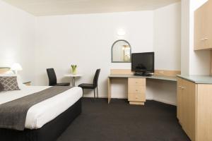 a hotel room with a bed, desk and a computer at Adelaide Riviera Hotel in Adelaide