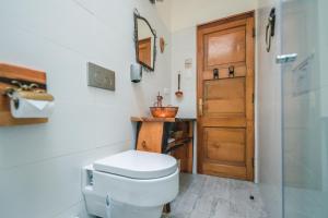La salle de bains est pourvue de toilettes et d'une porte en bois. dans l'établissement AYCA La Flora Hotel Boutique, à Valparaíso