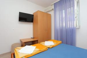 Pokój z dwoma łóżkami i telewizorem na ścianie w obiekcie Double Room Tucepi 5263f w Tučepi