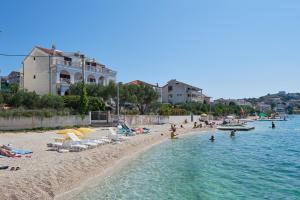 ein Strand mit Stühlen und Menschen im Wasser in der Unterkunft Apartments by the sea Okrug Gornji, Ciovo - 9694 in Trogir