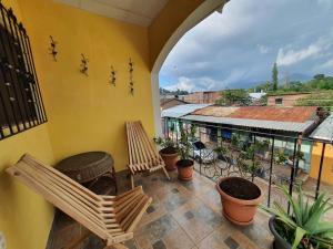 un balcón con 2 sillas, una mesa y algunas plantas en Hostal Las Veraneras Ataco en Concepción de Ataco