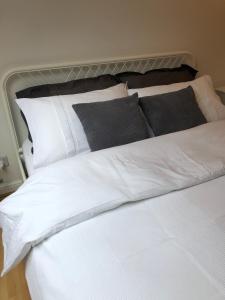 un letto bianco con cuscini neri sopra di Entire house Jersey farm St Albans a Saint Albans