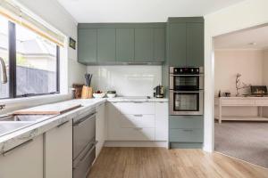 a kitchen with white counters and green cabinets at Quiet and cosy in Waikanae