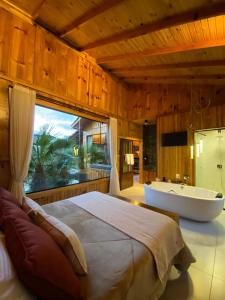 - une chambre avec un grand lit et une baignoire dans l'établissement Pousada- Cabana Gala Vale das Macieiras Urubici, à Urubici