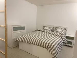 1 dormitorio con 1 cama con edredón de rayas blanco y negro en Charming intim apartment in Paris South, en Montrouge