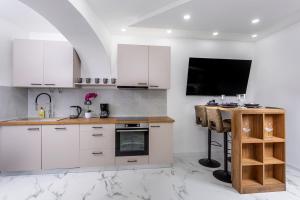 a kitchen with white cabinets and a desk with a television at Villa Nela Apartments in Crikvenica