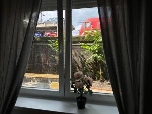 Una ventana con un jarrón de flores en el alféizar. en Railway Ljubljana ROOMS, en Liubliana