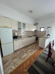 cocina con armarios blancos y suelo de mármol en Apartments with a parking space Kastel Sucurac, Kastela - 21585, en Kaštel Sućurac