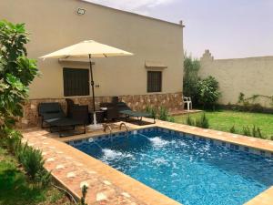una piscina con ombrellone, sedie e tavolo di Amazing Home in Agafay area a Marrakech