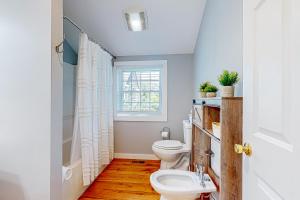 a bathroom with a toilet and a window at Island Time in Vineyard Haven