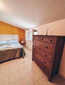a bedroom with a wooden dresser and a bed at Salinello Beer Baita Affittacamere in Le Ripe