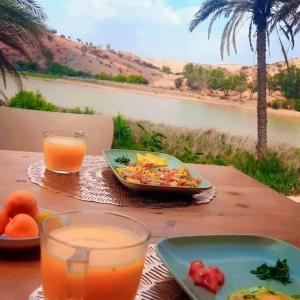 una mesa con un plato de comida y un tazón de zumo en Lake House Boulaouane en El Jadida