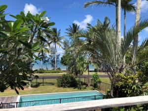 una piscina frente a algunas palmeras en Ohana - Beachfront Holiday House, en South Mission Beach