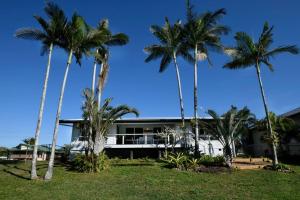 Un edificio con palmeras delante. en Ohana - Beachfront Holiday House, en South Mission Beach