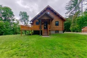 a log cabin with a large deck on a grass field at Secluded Haven - Entire House in Wevertown