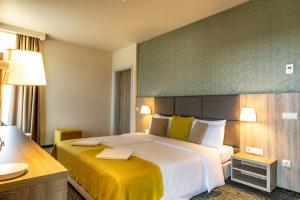 una habitación de hotel con una cama grande con sábanas amarillas en Lignum Hotel, en Miskolctapolca