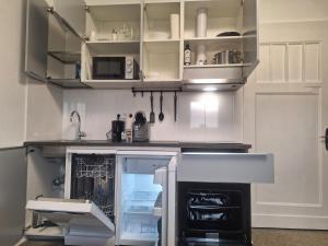 Studio Apartment 23 - 3R2 في إيسن: مطبخ مع دواليب بيضاء وثلاجة مفتوحة