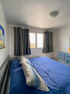 een slaapkamer met een blauw bed en ramen bij Hermoso apartamento con acceso al club in Puerto Palenque