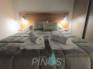 a bed with towels and pillows on top of it at Departamento Entre Pinos in San Carlos de Bariloche