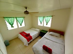 a small bedroom with two beds and two windows at Philomena's Lodge in Douane