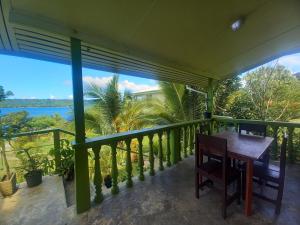 balcón con mesa, sillas y vistas al océano en Philomena's Lodge en Douane