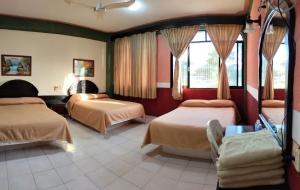 a hotel room with two beds and two windows at Hotel Real del Quijote a sólo 50 metros de la playa in Tecolutla