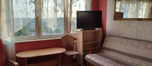 a room with a tv and a chair and windows at Apartament z baldachimem i pięknym widokiem Olsztyna in Olsztyn