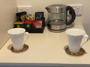 two cups sitting on a counter with a coffee pot at Te Whare Ma in Kerikeri