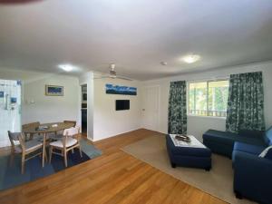 un salon avec un canapé bleu et une table dans l'établissement Mission Dreaming - 1 Bedroom Cottage, à South Mission Beach