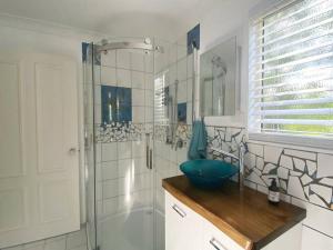 La salle de bains est pourvue d'une douche et d'un bol bleu sur un comptoir. dans l'établissement Mission Dreaming - 1 Bedroom Cottage, à South Mission Beach 7 autres photos
