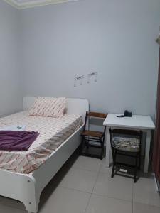 um pequeno quarto com uma cama e uma mesa em Hotel Amanhecer em São Paulo
