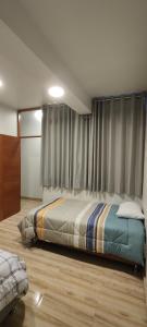 1 dormitorio con 1 cama y una ventana con cortinas en Estancia Familiar, en Oxapampa