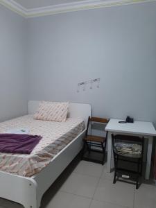 um quarto branco com uma cama e uma mesa em Hotel Amanhecer em São Paulo