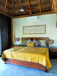 a bedroom with a bed with a yellow bedspread at Villa Ensueño, Lagoon Private Front in Bacalar
