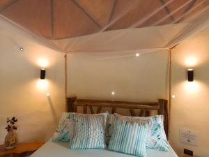 a bed in a tent with two pillows on it at Mi casa es tu casa Glamping in Capurganá