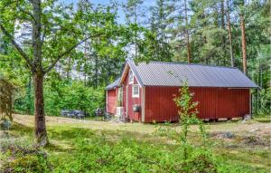 um celeiro vermelho no meio de uma floresta em 1 Bedroom Gorgeous Home In Norrtlje em Norrtälje