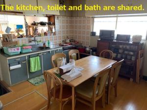 a kitchen with a wooden table and chairs and a kitchen and counters at 磯ノ浦駅前ゲストハウス 月と空moon and sky in Wakayama