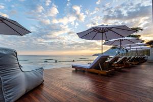 una terraza con sillas y sombrillas en la playa en Duke Beach Hotel Maresias, en Maresias