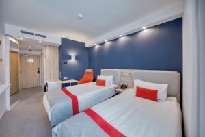 a hotel room with two beds and an orange chair at Holiday Inn Express - Yerevan by IHG in Yerevan