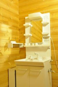 y baño con lavabo blanco y espejo. en Log Cottage be with nature, en Furano