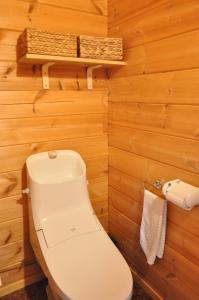 uma casa de banho com WC numa parede de madeira em Log Cottage be with nature em Furano