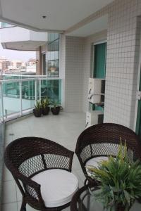 2 sillas de mimbre y una mesa en el balcón en Confortável apartamento na Praia do Forte, en Cabo Frío